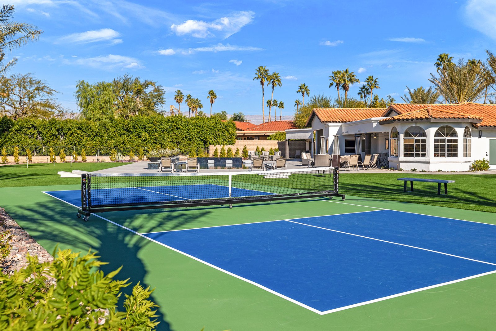 Blue and green pickleball court with the house and outdoor seating behind at Court Dreams Estate in Bermuda Dunes