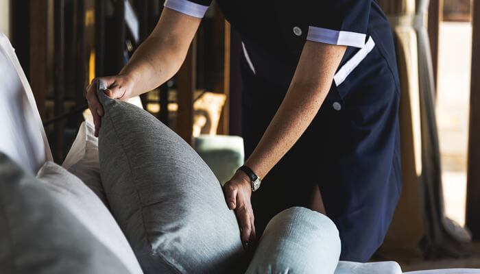 A housekeeping attendant refreshing pillows in a guest room