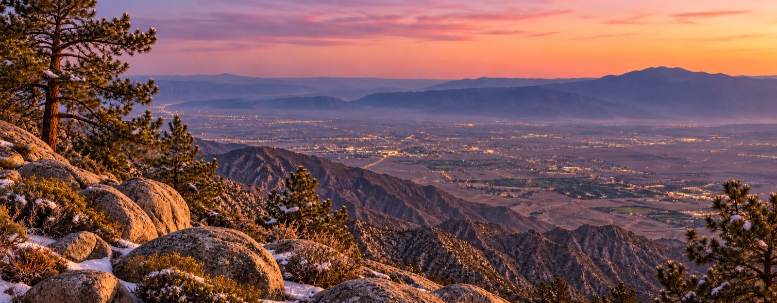 A dusting of snow on granite and pines above the Coachella Valley at twilight